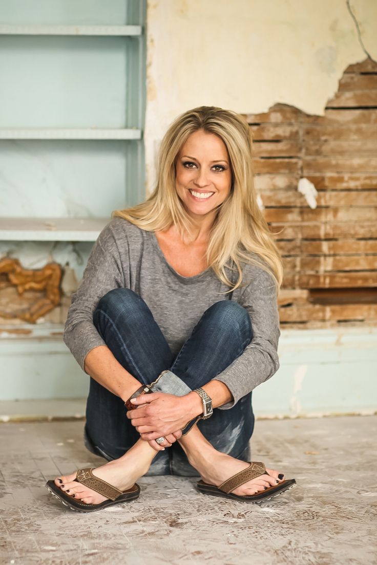 a woman is sitting on the floor with her legs crossed and smiling at the camera