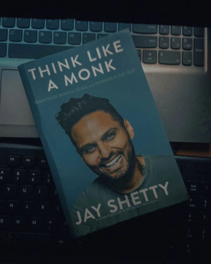 a book sitting on top of a laptop computer next to a keyboard with the title think like a monk