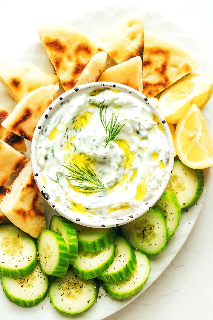 cucumber slices and pita chips on a plate with tzap, dip