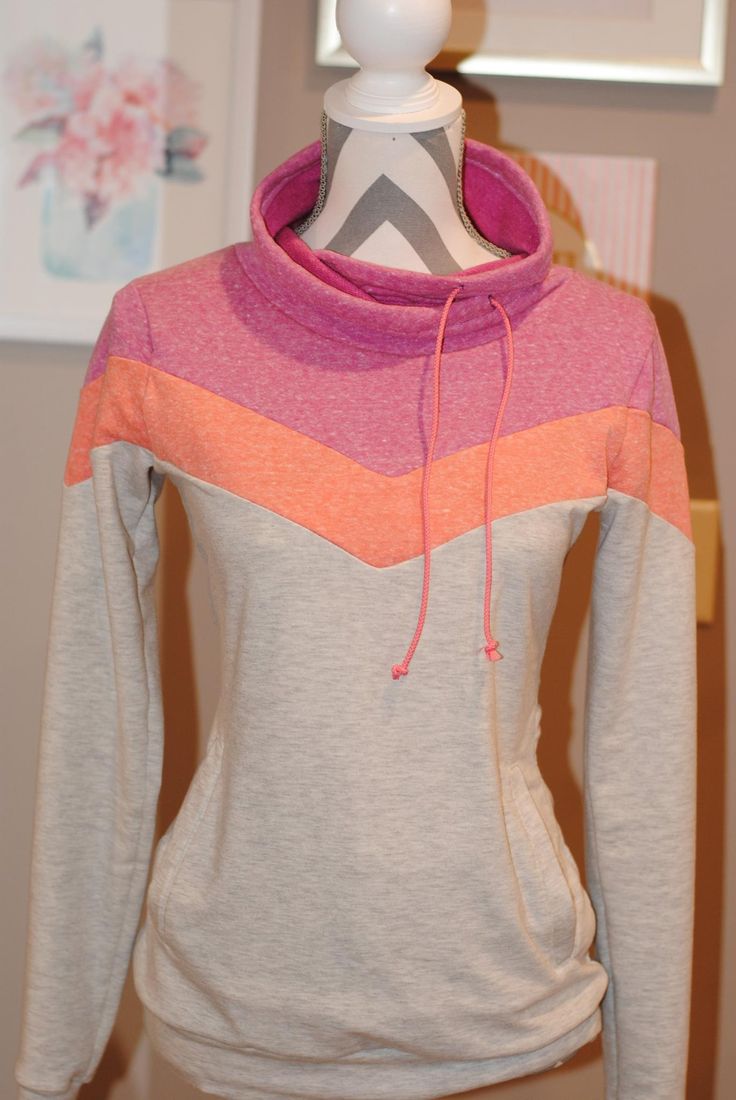 a white mannequin wearing a gray and pink sweater with an orange hoodie