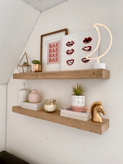 two wooden shelves with pictures, plants and other items on them in the corner of a room