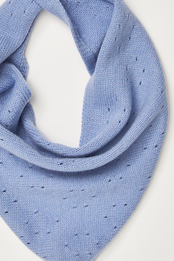 a blue knitted scarf with holes on the front and bottom, sitting on top of a white surface