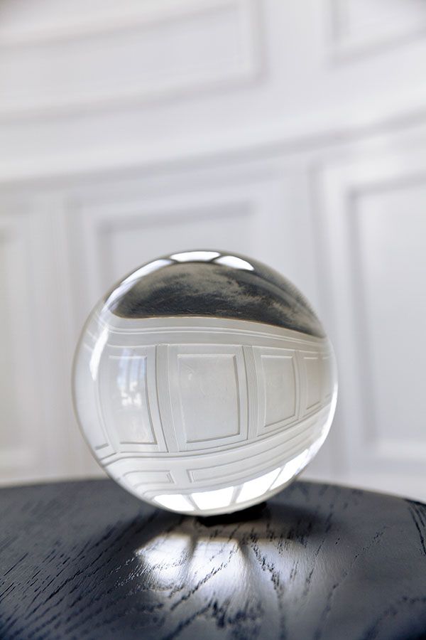 a glass ball sitting on top of a wooden table next to a white wall and ceiling