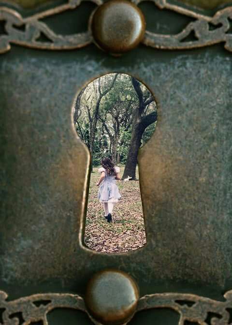 a girl in a white dress is seen through an old metal frame with a keyhole