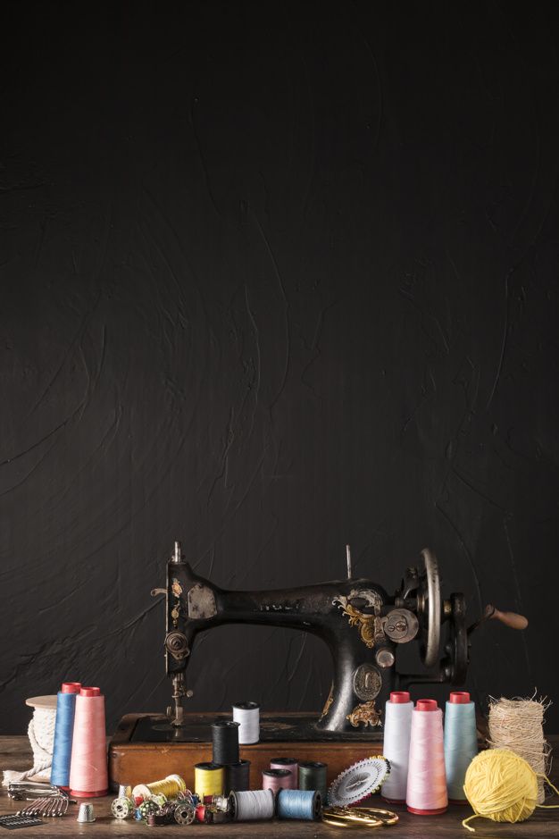 an old sewing machine sitting on top of a wooden table next to spools of thread