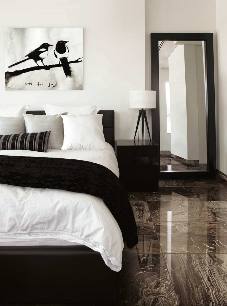 a bedroom with white walls, black and white bedding and artwork on the wall