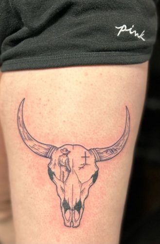 a bull's skull tattoo on the side of a woman's thigh,