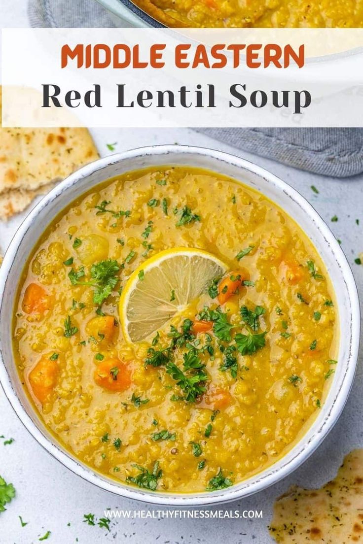 a white bowl filled with red lentil soup and topped with a slice of lemon