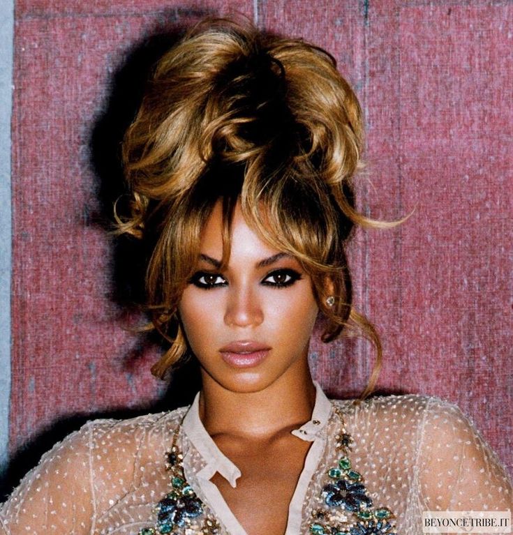 a close up of a person wearing a shirt and hair in a bun with some beads on it