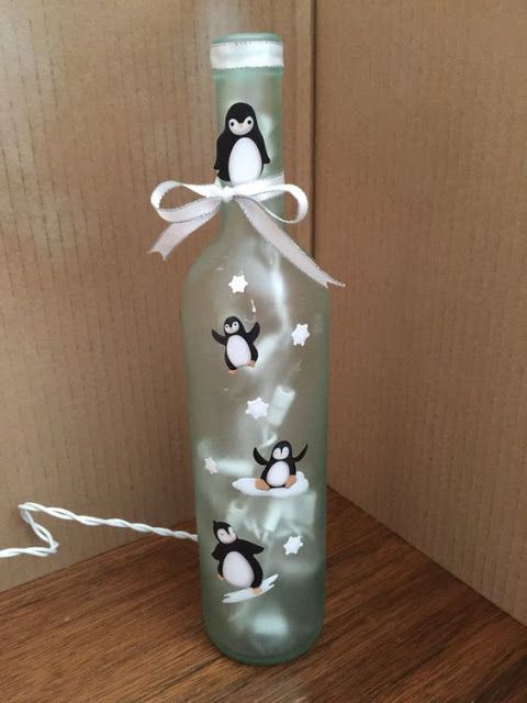 a bottle with penguins painted on it sitting on top of a wooden table next to a wall