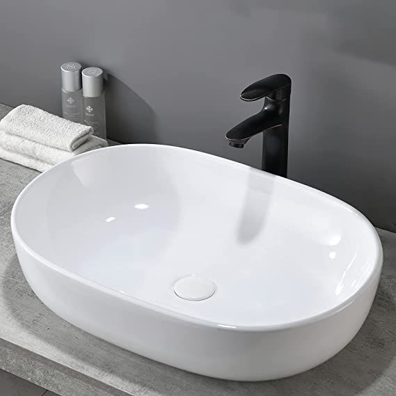 a white bowl sink sitting on top of a counter next to a vase with flowers