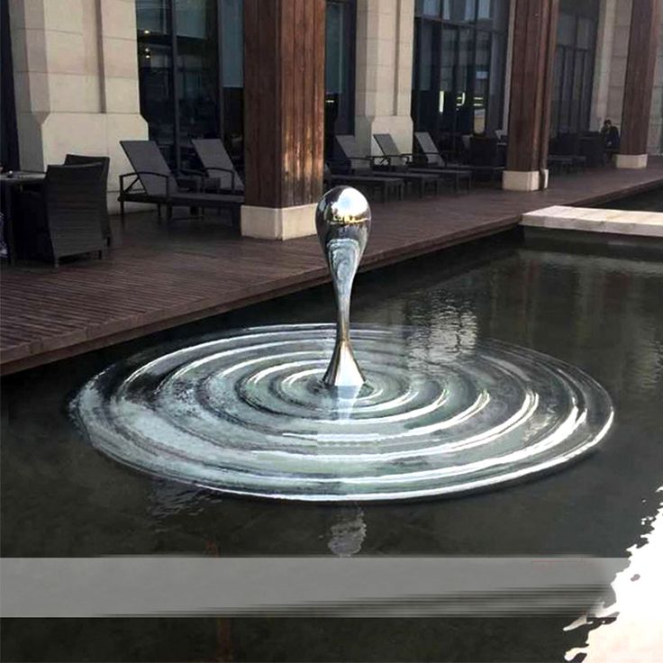 an artistic fountain in the middle of a pool