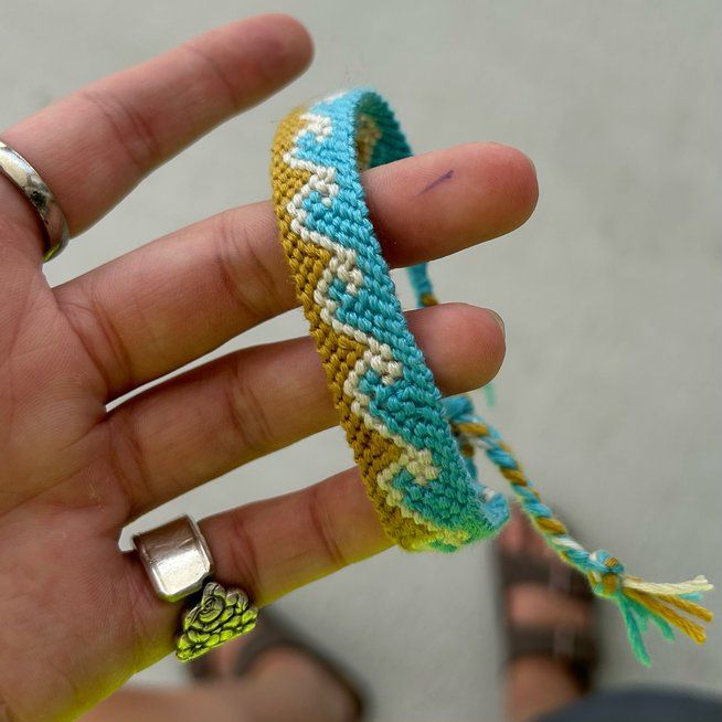 a hand holding a bracelet with two rings on it and a beaded band around the wrist