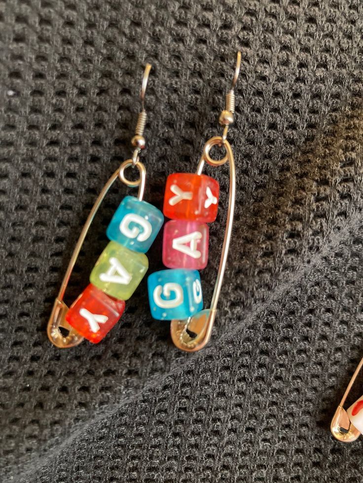 two pairs of earrings with numbers on them sitting on top of a gray cloth covered surface