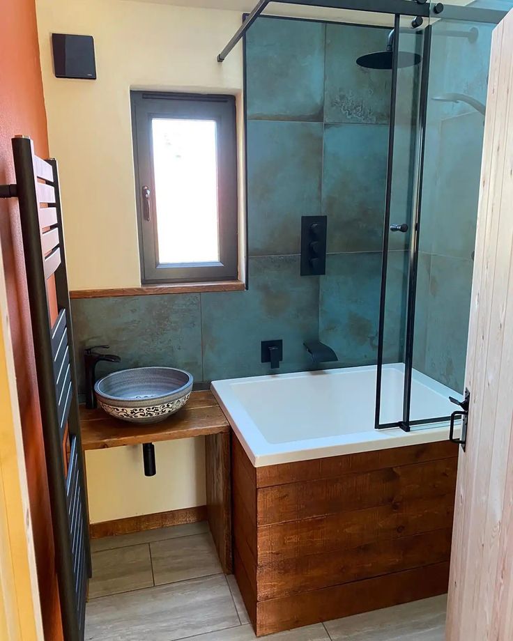 a bathroom with a tub, sink and window next to a wooden cabinet in the corner