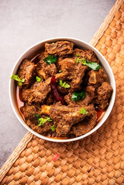 a white bowl filled with meat and garnished with cilantro