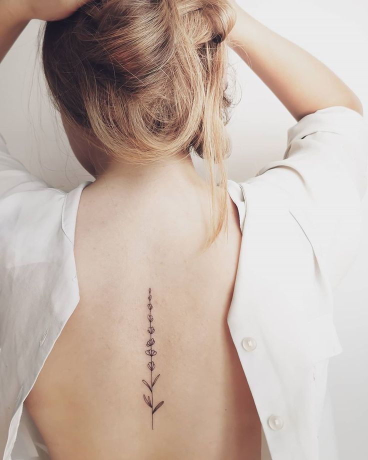 the back of a woman's neck with a flower tattoo on it