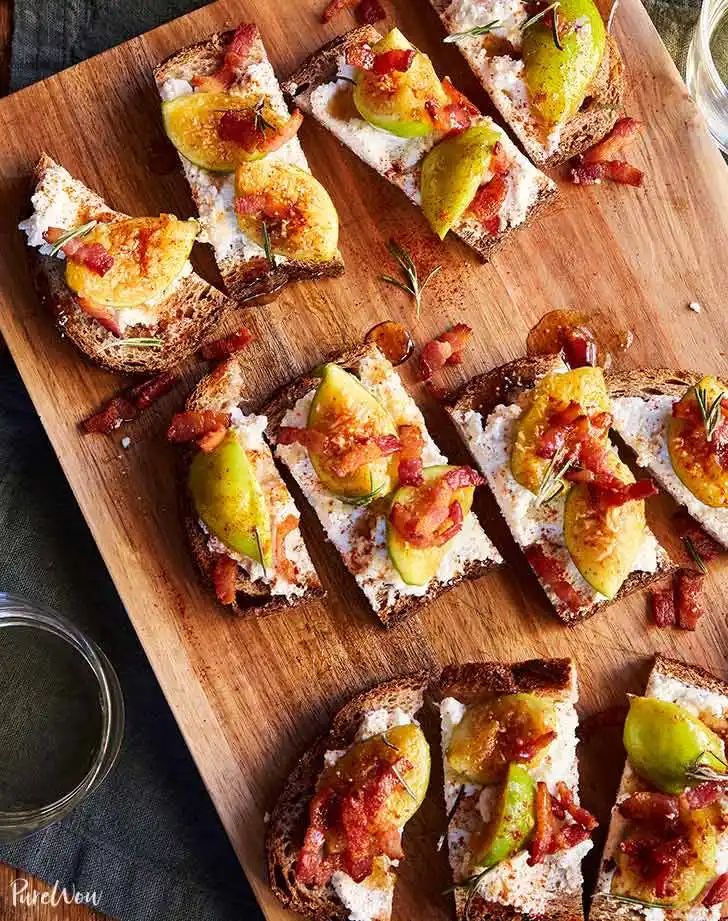 several pieces of bread with different toppings on them sitting on a wooden cutting board