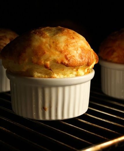 two muffins sitting in a white cup on top of an oven rack next to each other