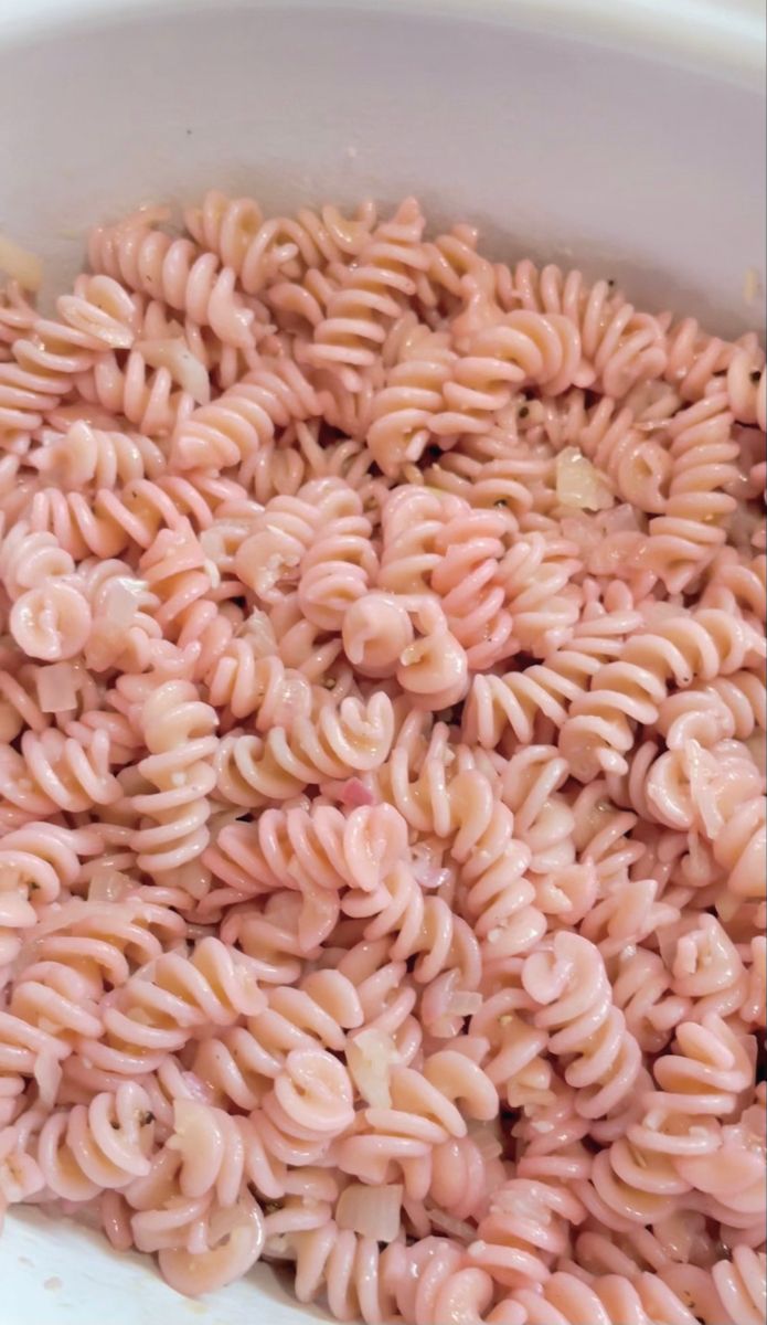 Pink rotini pasta in a serving bowl.