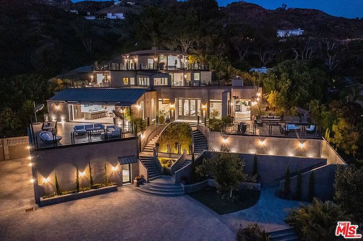 an aerial view of a house at night with lights on the front and stairs leading up to it