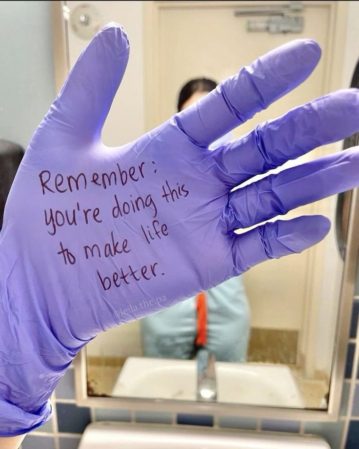 a purple glove with writing on it is in front of a bathroom sink and mirror