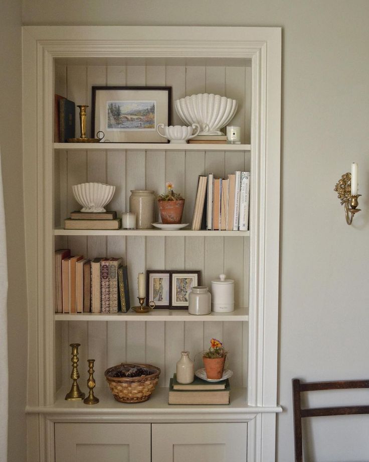 a bookshelf filled with lots of books next to a wall mounted candle holder