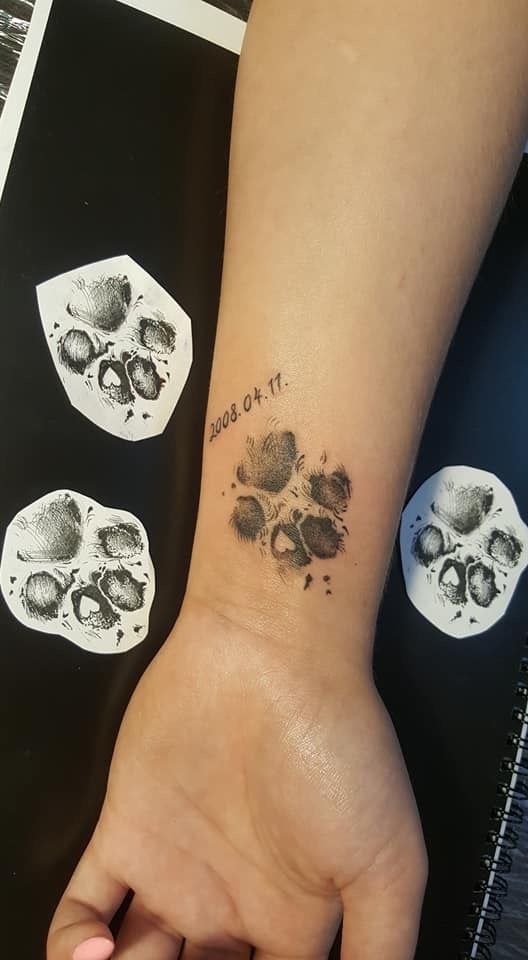 a person's hand with a tattoo on it and three skulls behind the wrist