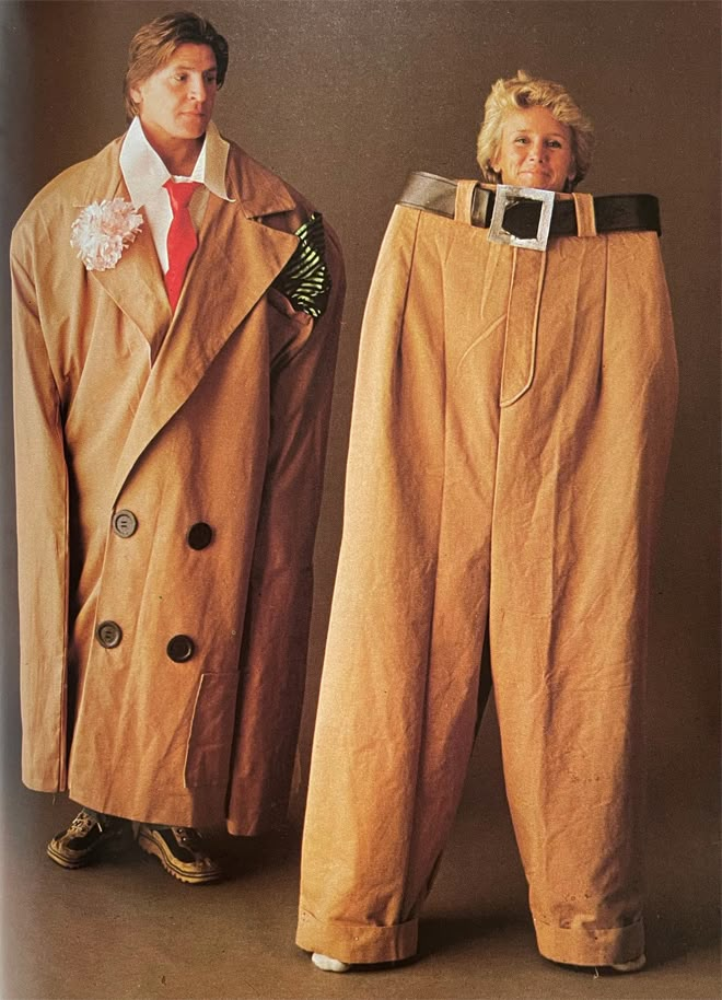 two men in trench coats standing next to each other wearing matching pants and jackets with buttons on the side