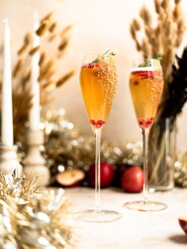 two champagne flutes with strawberries and garnishes on a table next to christmas decorations