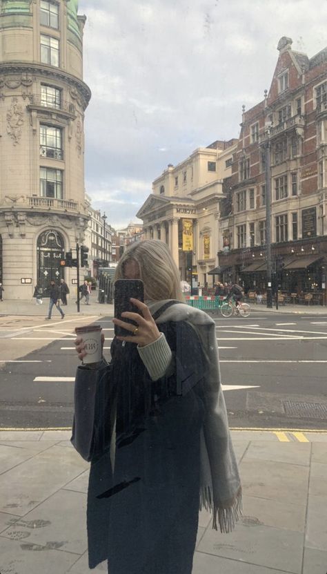 a woman taking a selfie with her cell phone on the sidewalk in front of buildings