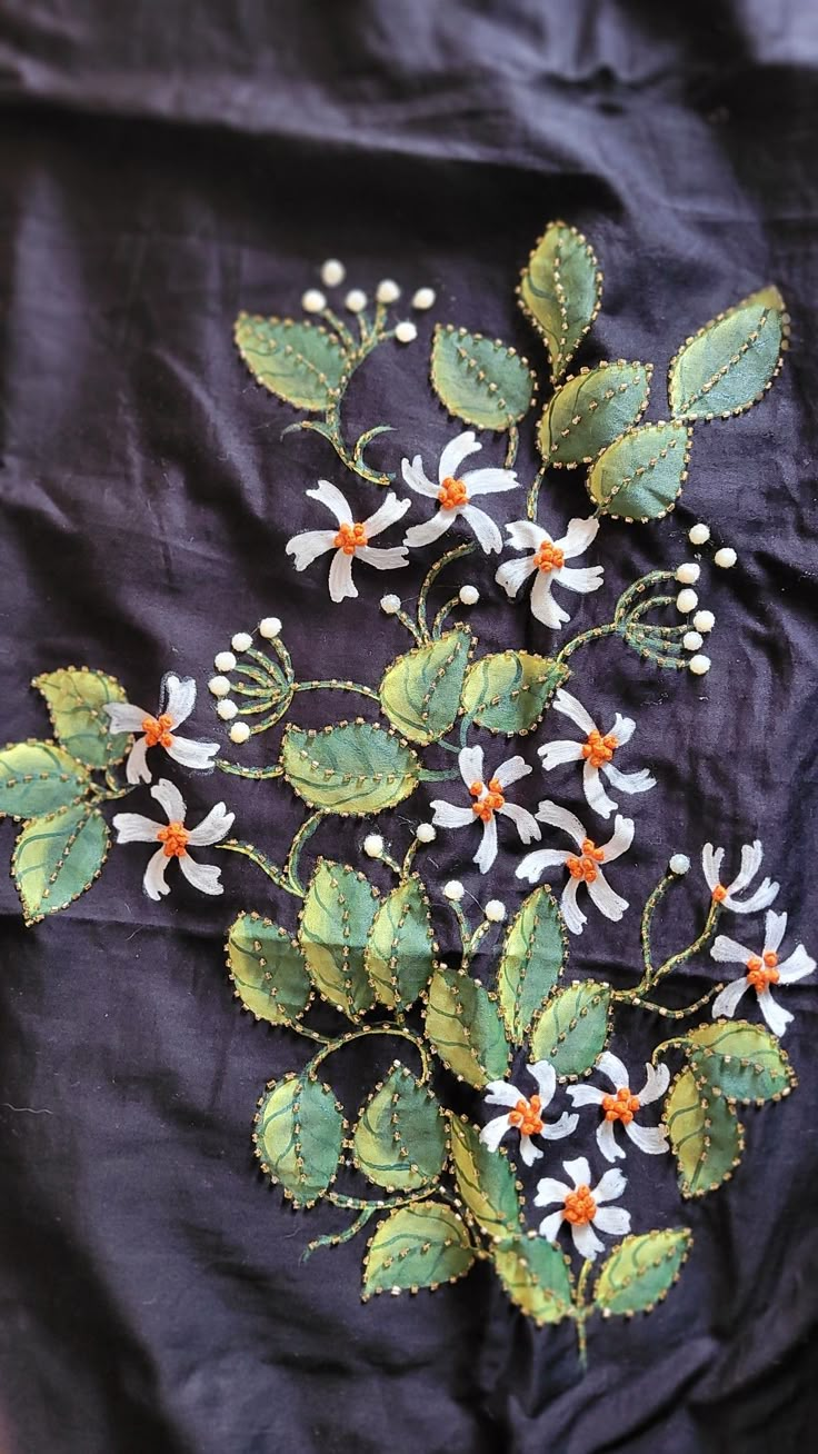 a black cloth with white and orange flowers on it's side, next to a green leafy plant