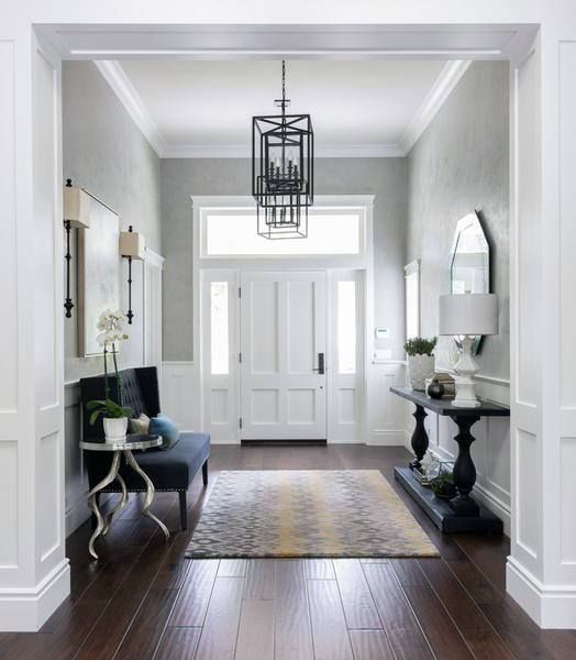 an entry way with white walls and wood flooring, chandelier above the door