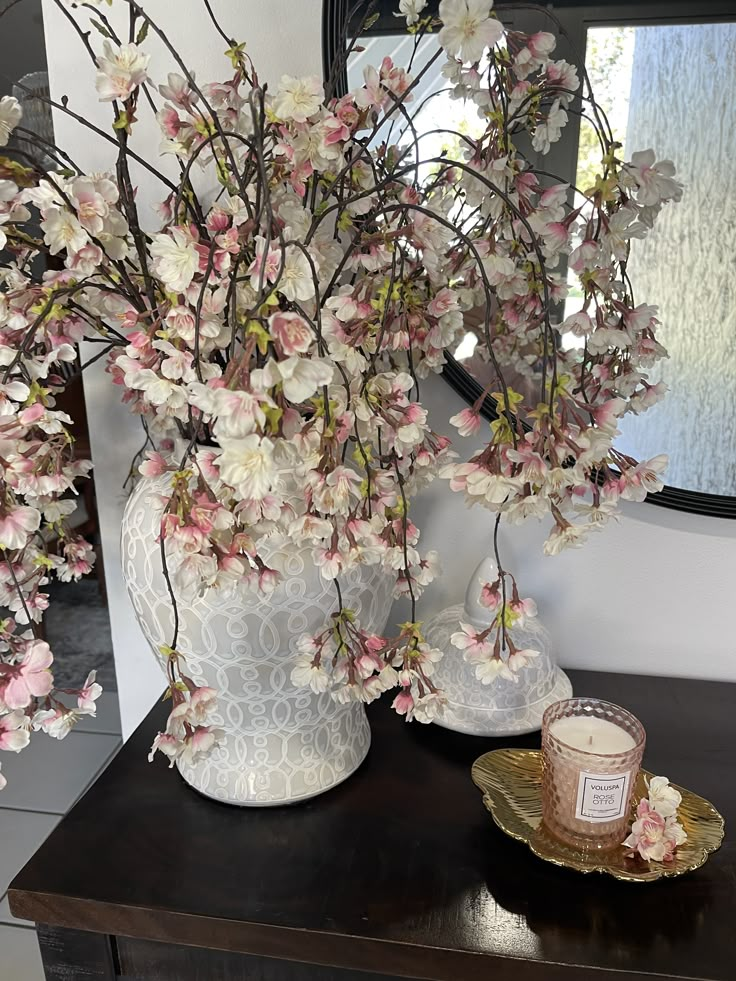 a vase filled with pink flowers sitting on top of a table next to a mirror