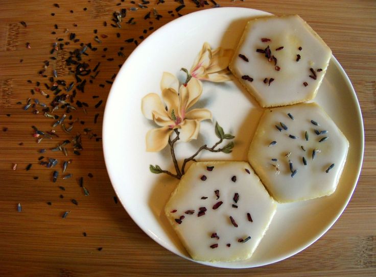 four pieces of soap on a plate with flowers and seeds scattered around the edge,