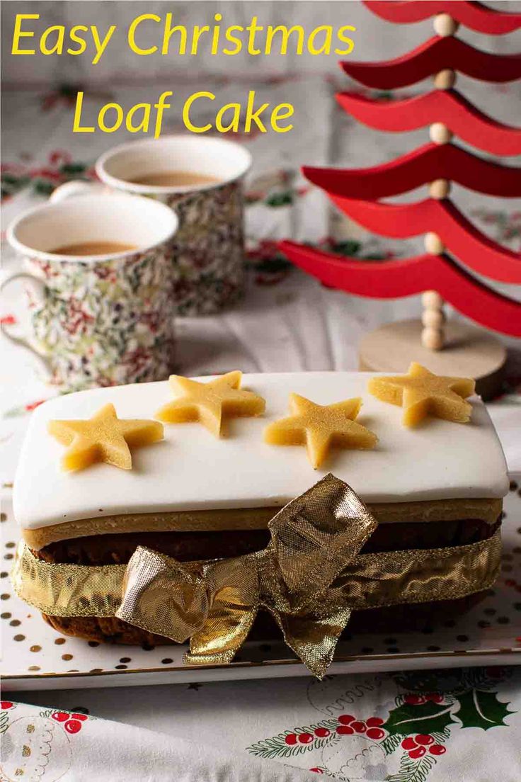 an easy christmas loaf cake with white frosting and star decorations on top, next to a cup of coffee