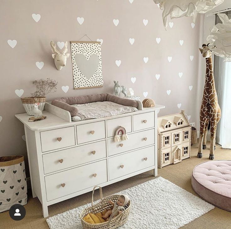 a baby's room with pink walls and white furniture