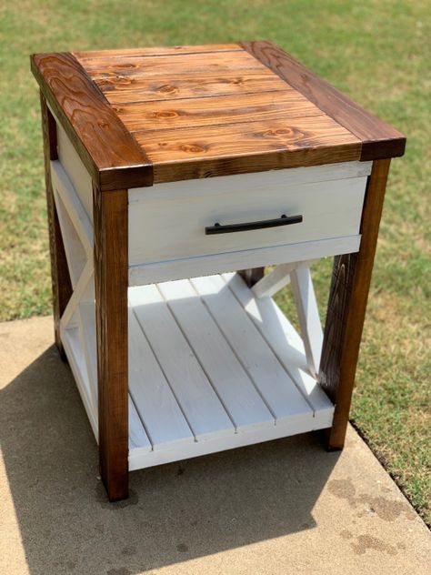 a small wooden table with drawers on the top and bottom, sitting in front of some grass