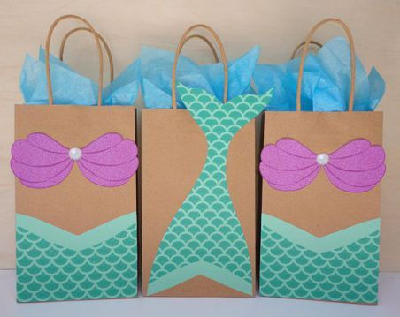 three bags with bows on them sitting in front of a white wall and blue tissue paper