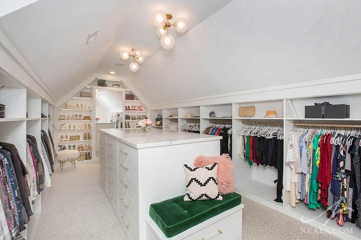 a closet with lots of clothes and shoes on the shelves, including a green bench