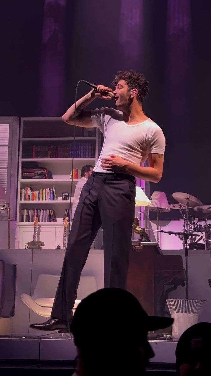 a man standing on top of a stage holding a microphone in front of his face