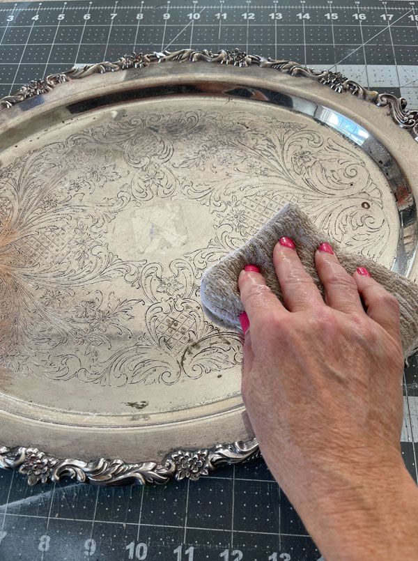 a woman cleaning a silver tray with a cloth