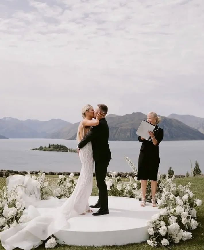 the bride and groom are getting married in front of an outdoor ceremony setup with white flowers