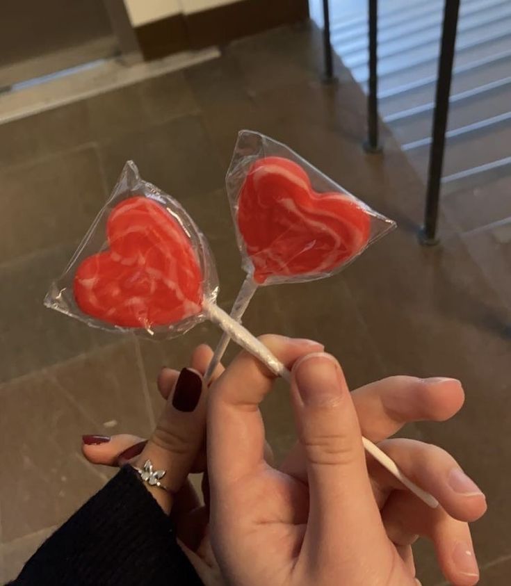 someone is holding two lollipops with hearts on them