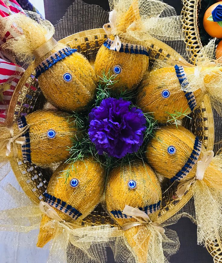 a basket filled with oranges and purple flowers on top of a table next to other decorations