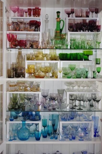 a shelf filled with lots of different colored glassware