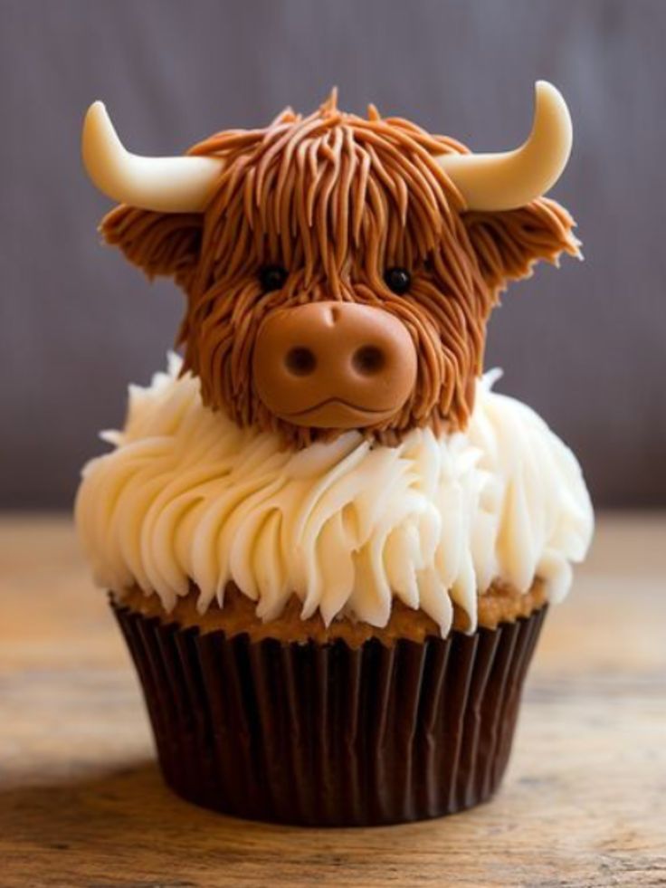 a cupcake with white frosting and a brown cow's head on top