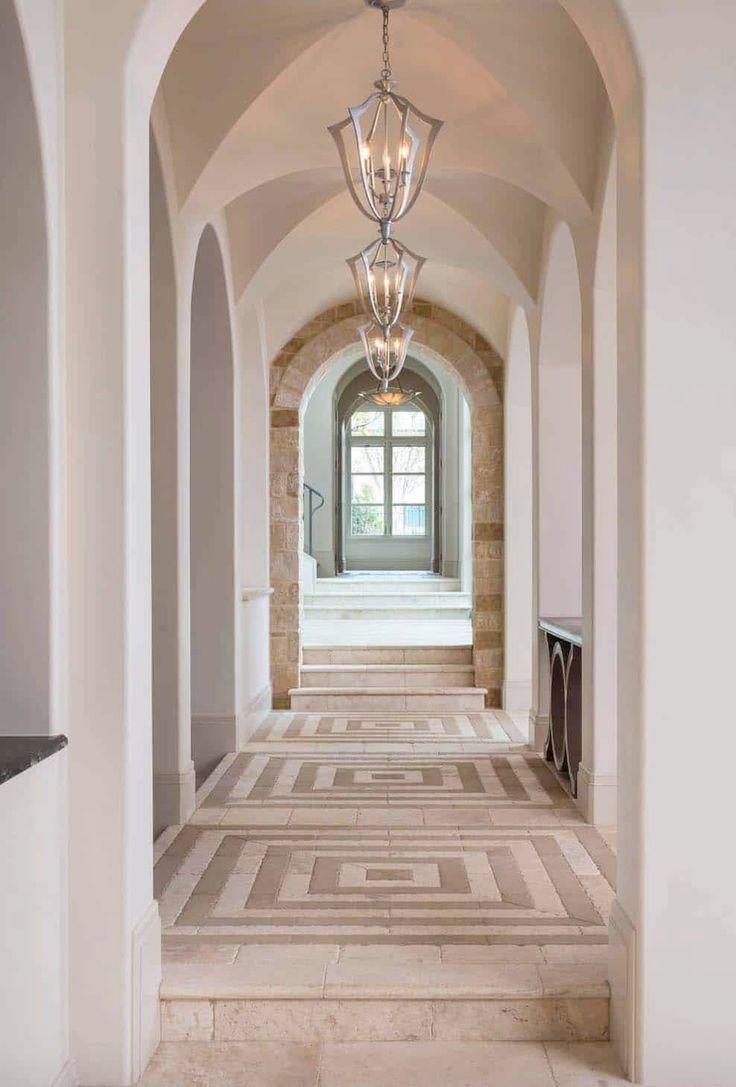 an arched hallway leading to the front door and entry way with light fixtures on either side