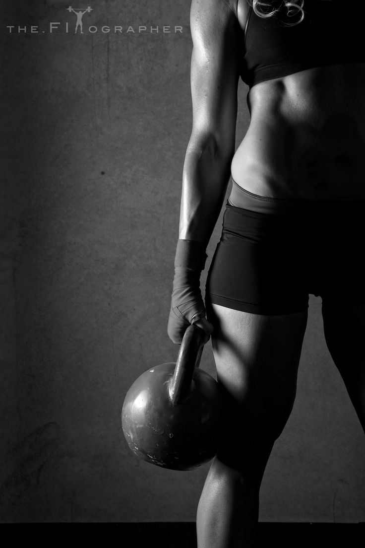 a black and white photo of a female bodybuilt holding a medicine ball