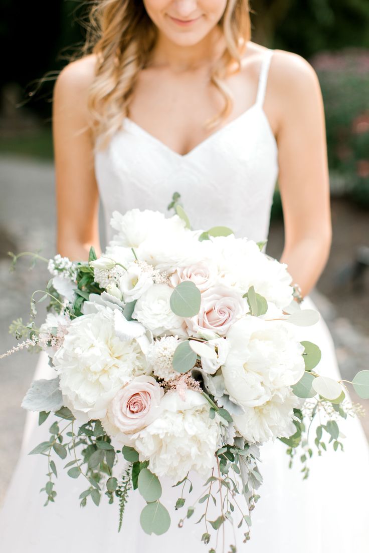 a bride holding a bouquet of white and pink flowers